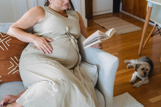Pregnant woman reading a book, resting during early labor. Birth doula in Provo, Utah